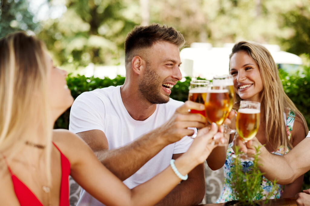 Group of happy friends toasting with beer at the summer bar